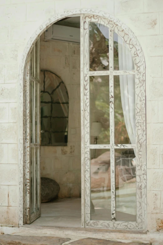 large arch door with mirrored glass in white brick building