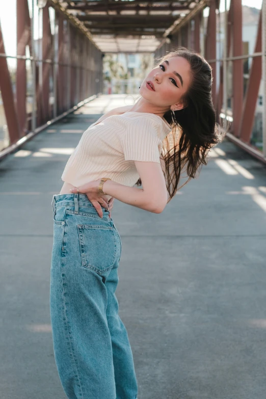 a girl is posing for the camera wearing wide denim pants and white tee shirt