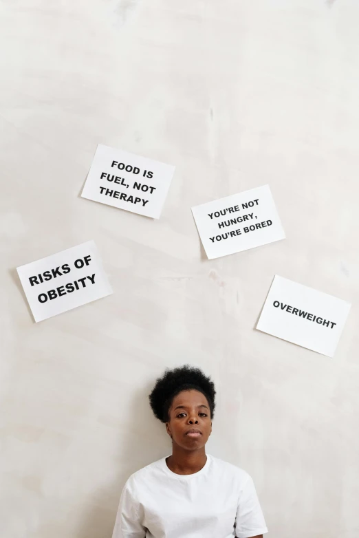 a woman sits against a wall with some signs on it