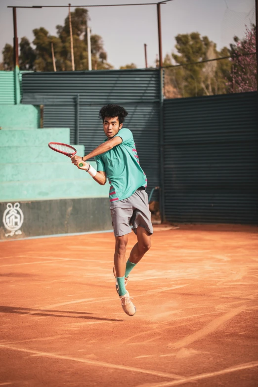 a young man playing tennis on a red clay court