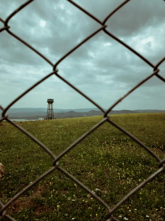 the green field is behind the fence and water tower