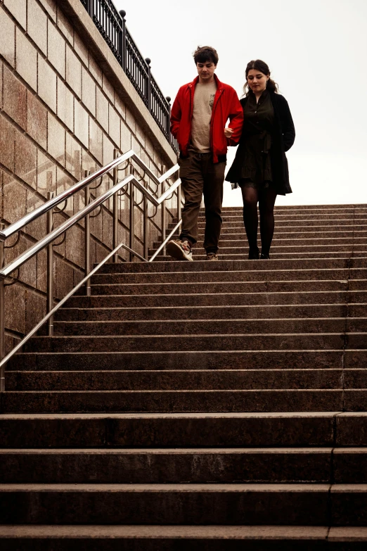 a couple walks up the stairs while the woman walks down