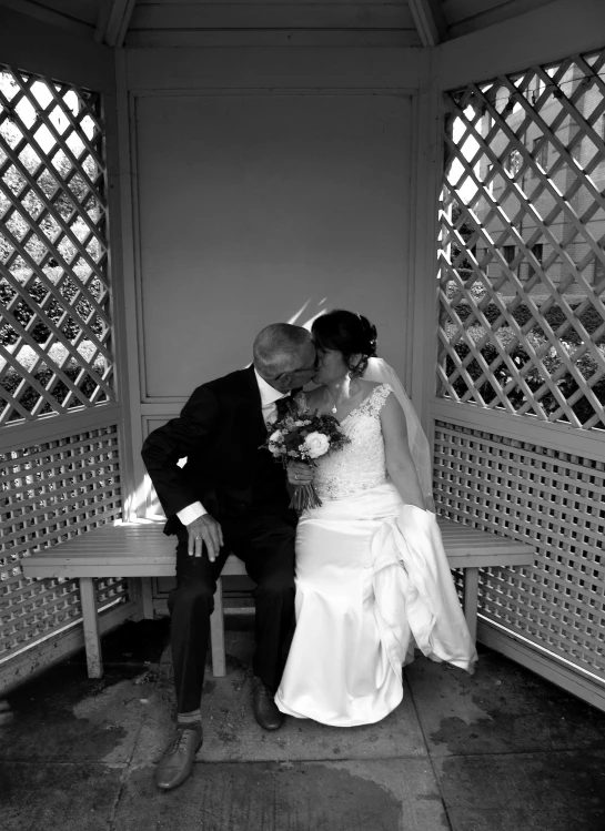 a bride and groom kiss on a bench in the gazebo