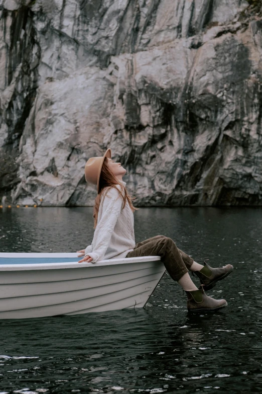 a girl sitting in a boat looking out at some mountains