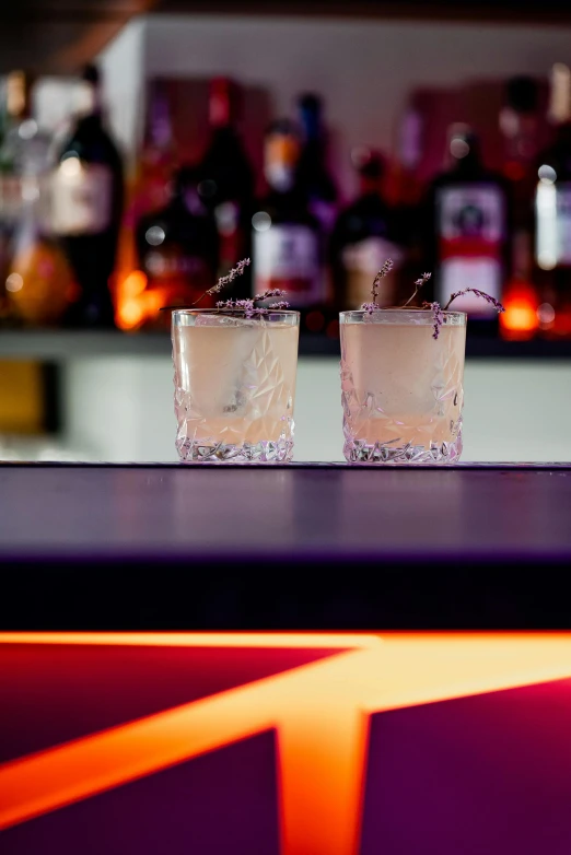 two glasses filled with vodka on top of a bar