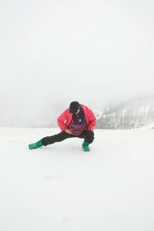 the person in the pink jacket is kneeling down on the snow