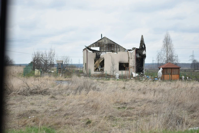 an old building sits in a field with other buildings in the background