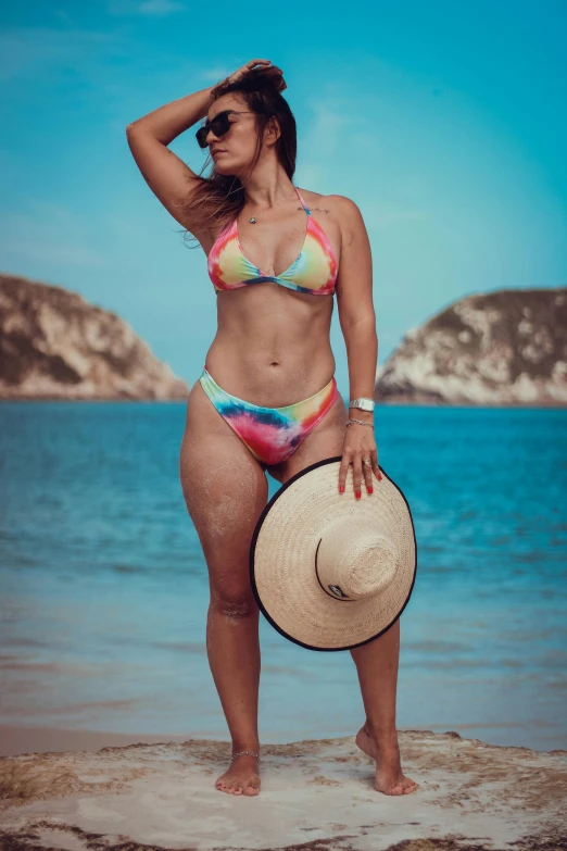 a beautiful woman in a bikini stands by the ocean