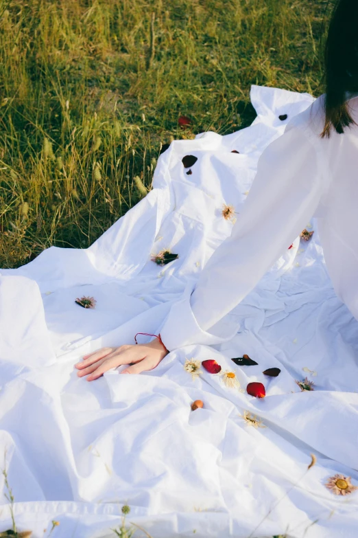 a woman lying in the grass with flowers on a blanket