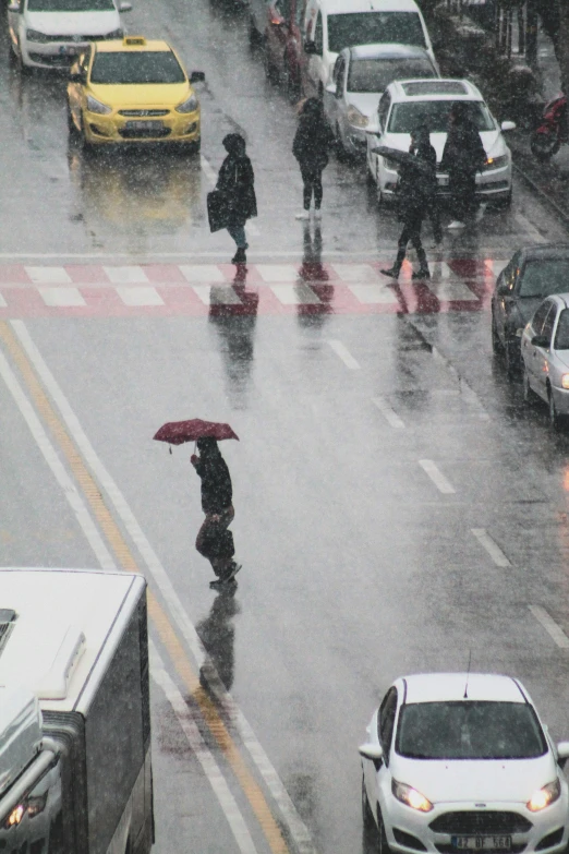 people walking across a wet road holding umbrellas