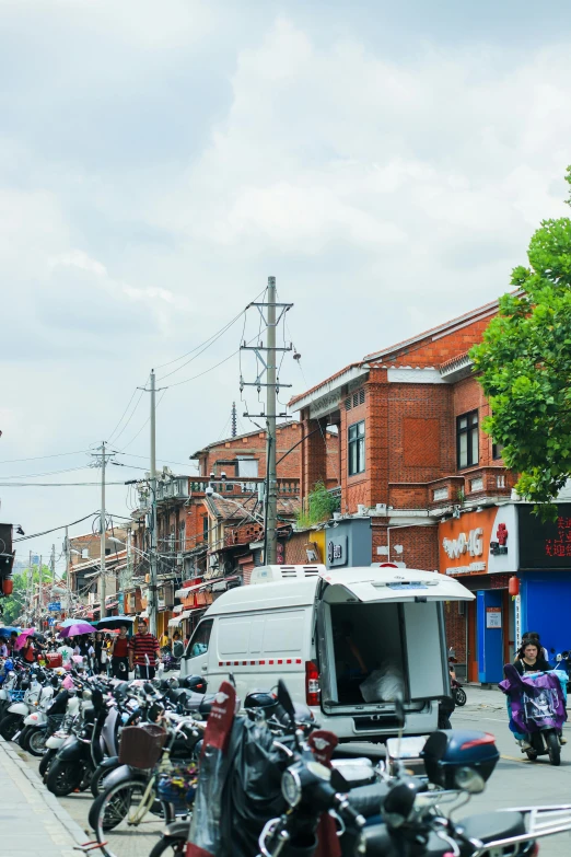 lots of motorcycles are parked and people walk down the sidewalk