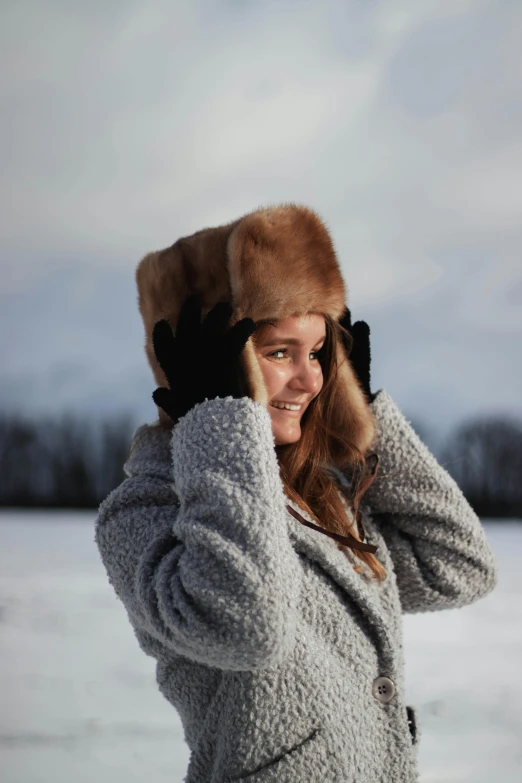 a woman with a winter hat and coat looks off into the distance