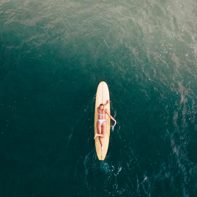 a woman sits on top of a surfboard floating in the ocean