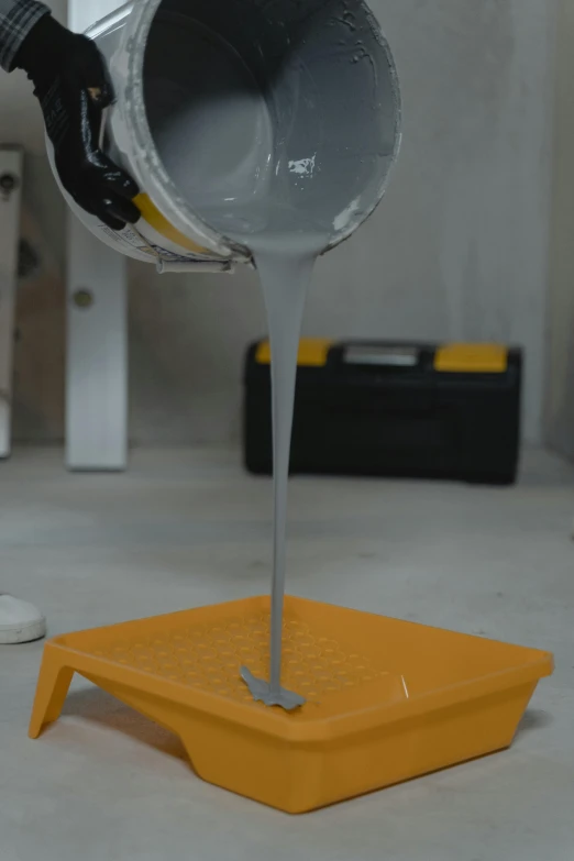 a man pouring a bucket of milk on top of a yellow table