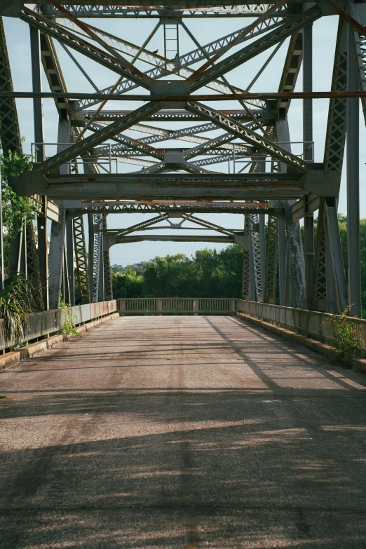 a road is going underneath a bridge with several metal pillars