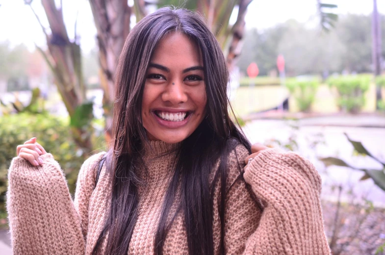 a woman smiling and holding her hand up