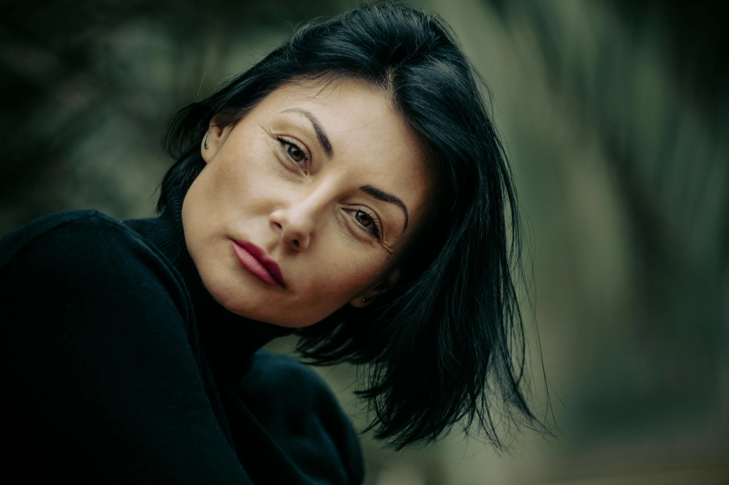 an asian woman with black hair has her chin resting on the top of her neck