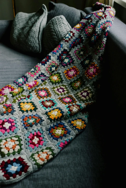 a large crocheted granny afghan is laying on a couch