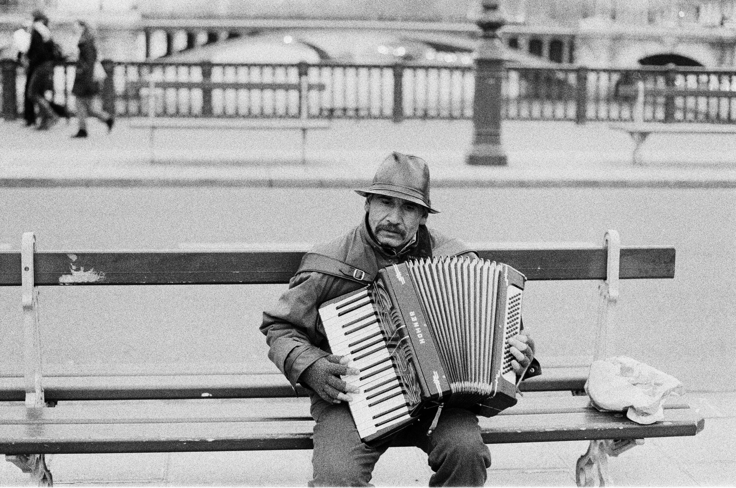 a man sitting on a park bench while holding an accordion