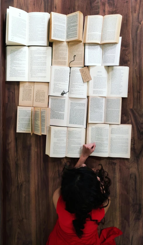 a woman is looking up at several books flying through the air