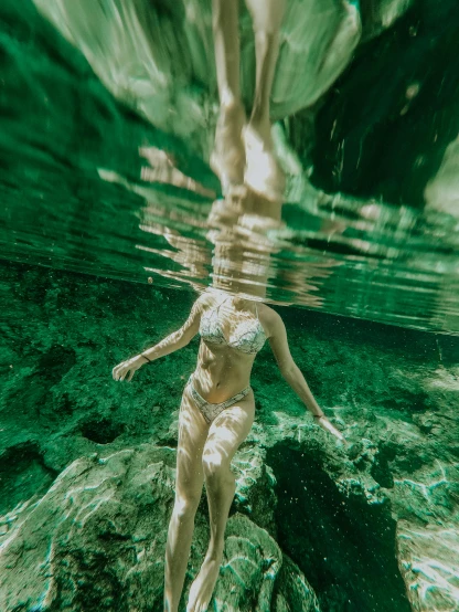 a woman in a bikini dives under a large body of water