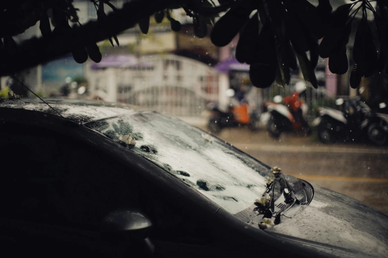 rain falling down on a parked vehicle in a city