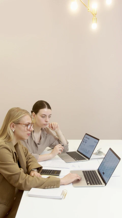 three girls sitting at a desk with laptops on it