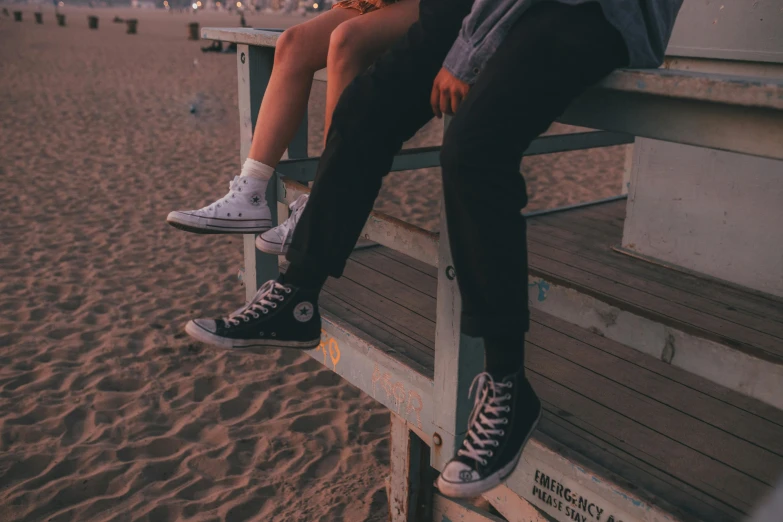 two people sitting together on the bench at a beach