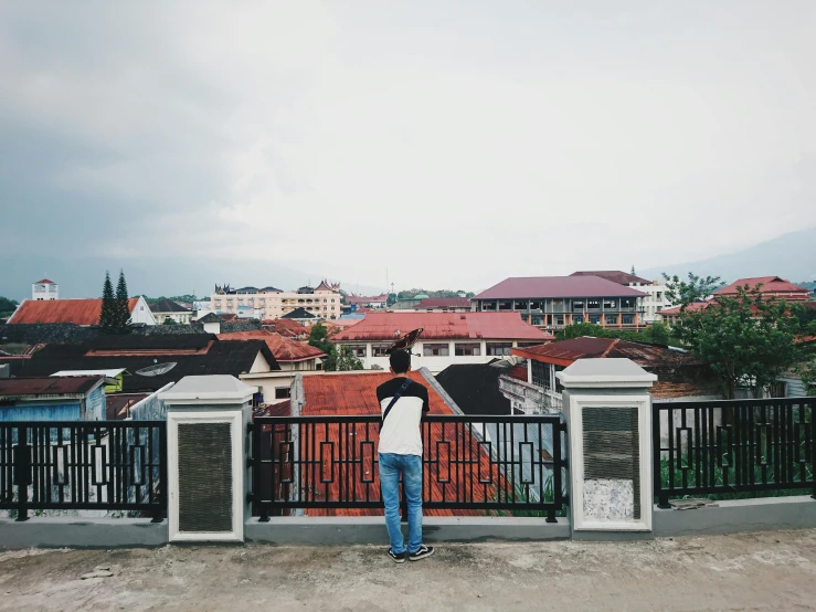 a person standing on a city ledge next to a fence