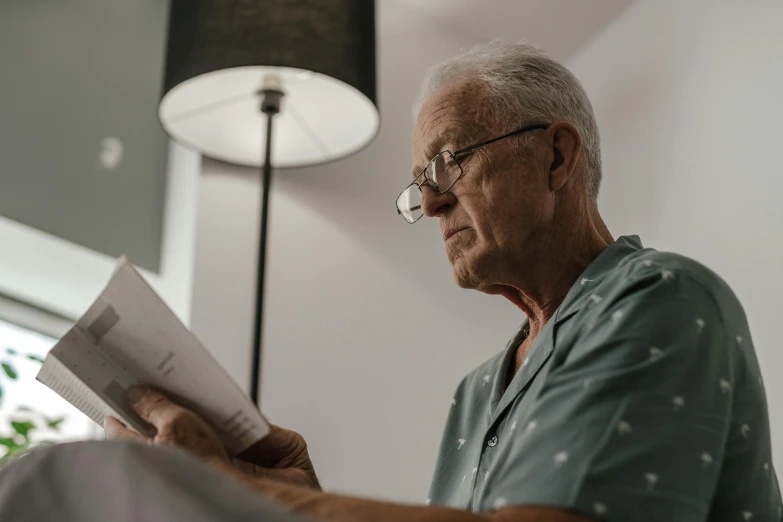 a man sitting at the edge of a dining room table reading a book