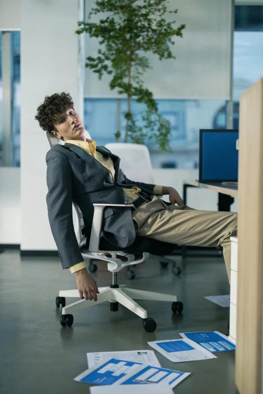 a man sitting in an office chair talking on his phone