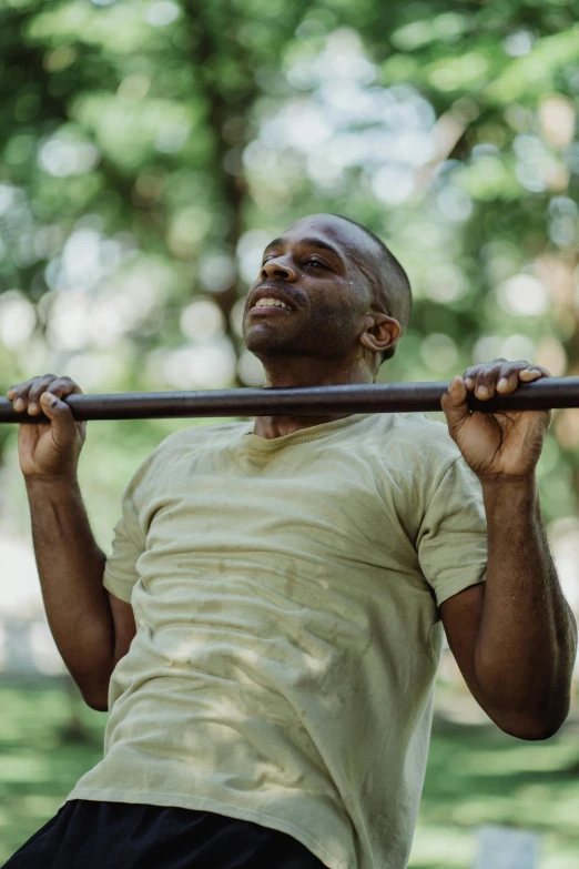 a black man is lifting a bar in the park