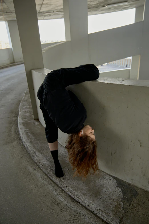 a woman leaning against a wall with her head against the edge