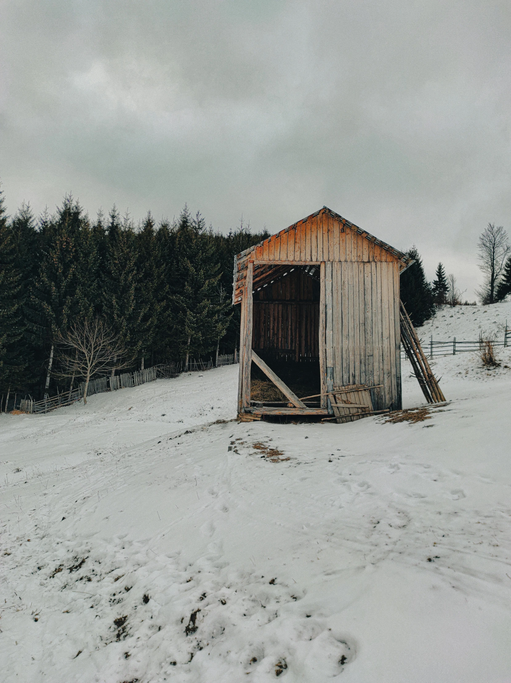 a snowy barn with the doors open in a field