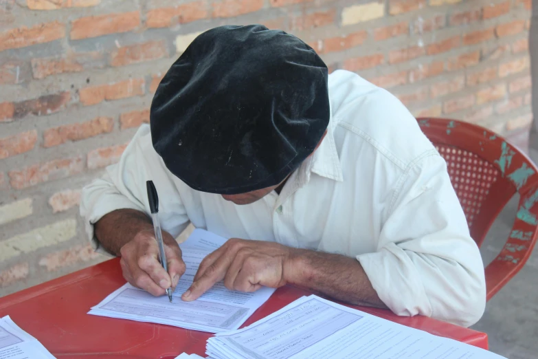 a man signing papers with a pen and a paper bag over his head