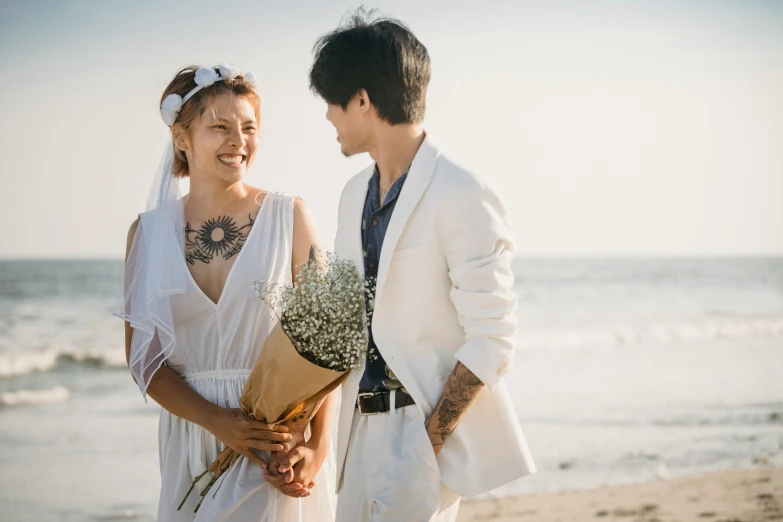 there is a man in a suit and woman in white at the beach