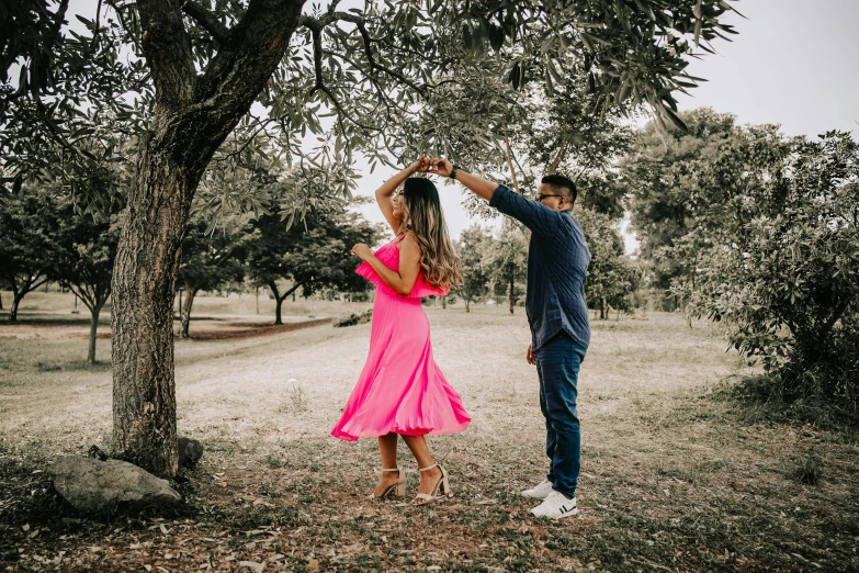 a man and woman dancing by a tree