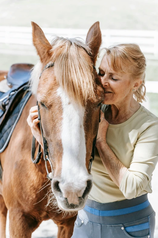 woman with blond hair standing next to a brown horse