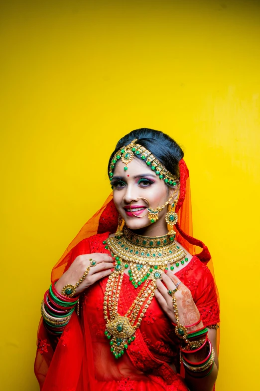 the smiling woman in red is wearing a veil and jewelry