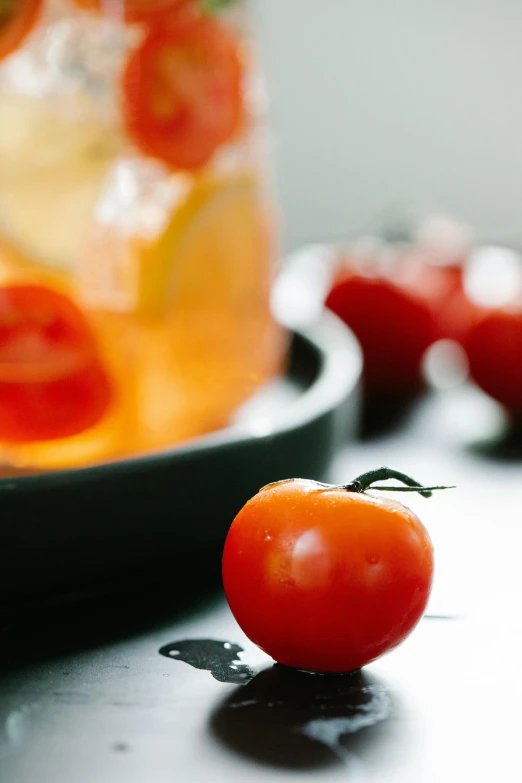 some tomatoes and other vegetables are next to a glass