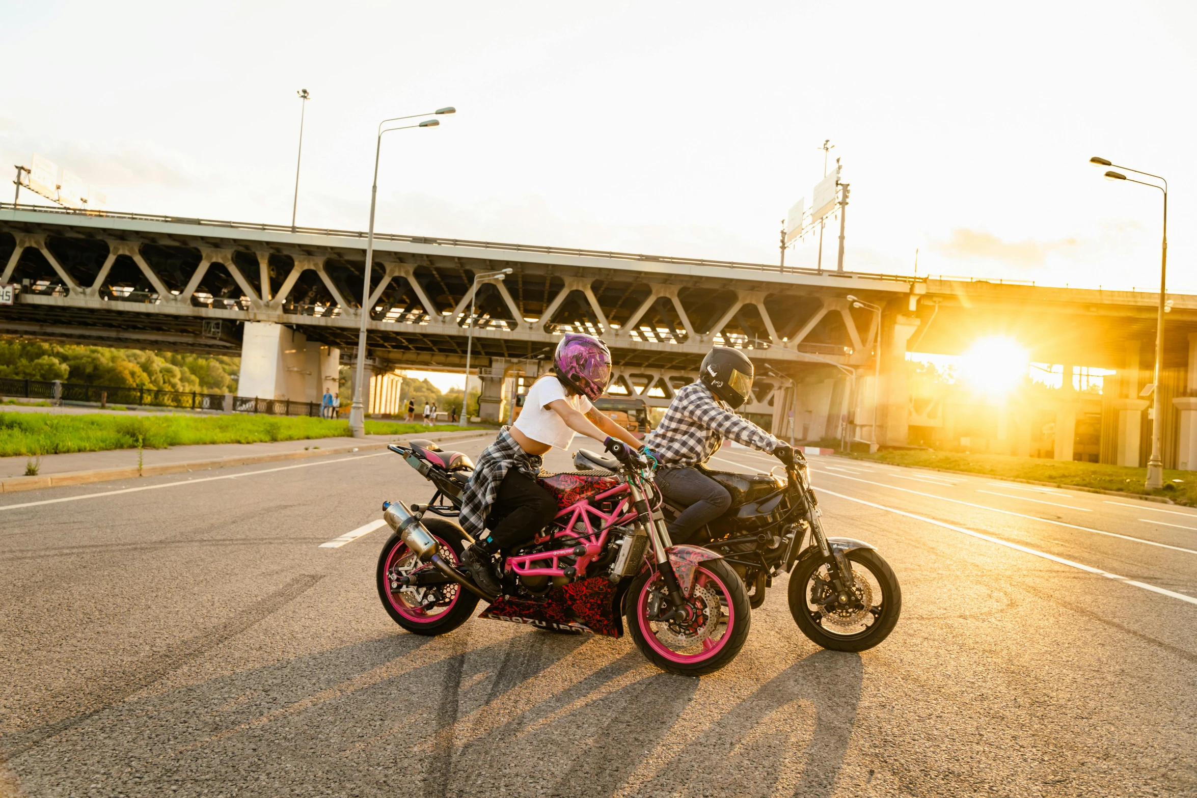 two people riding on the back of motor bikes