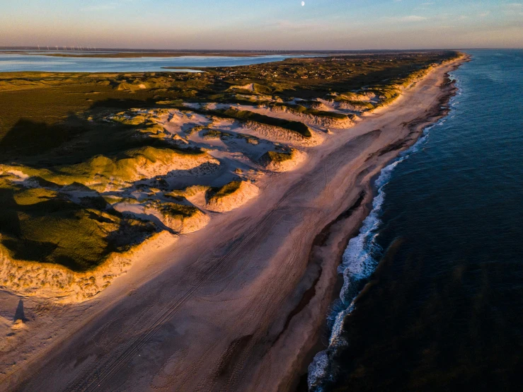 an empty beach next to an ocean under a bright blue sky