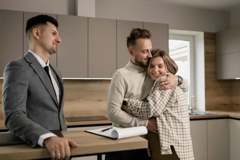 a woman and two men standing near a table in a kitchen