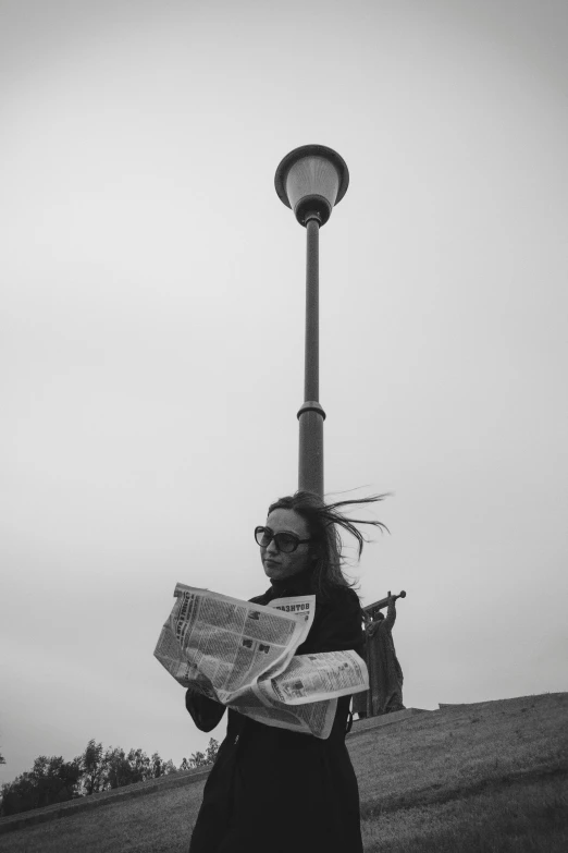 a black and white image of a person holding a newspaper
