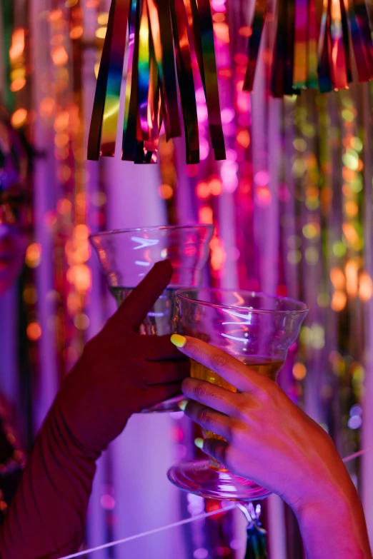 a person holding up a glass in front of some lights