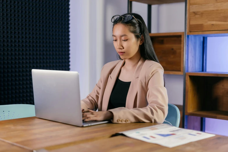 a young woman sits at a table using a laptop