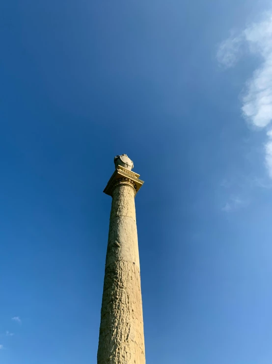 a tall cement pillar stands in a grassy field