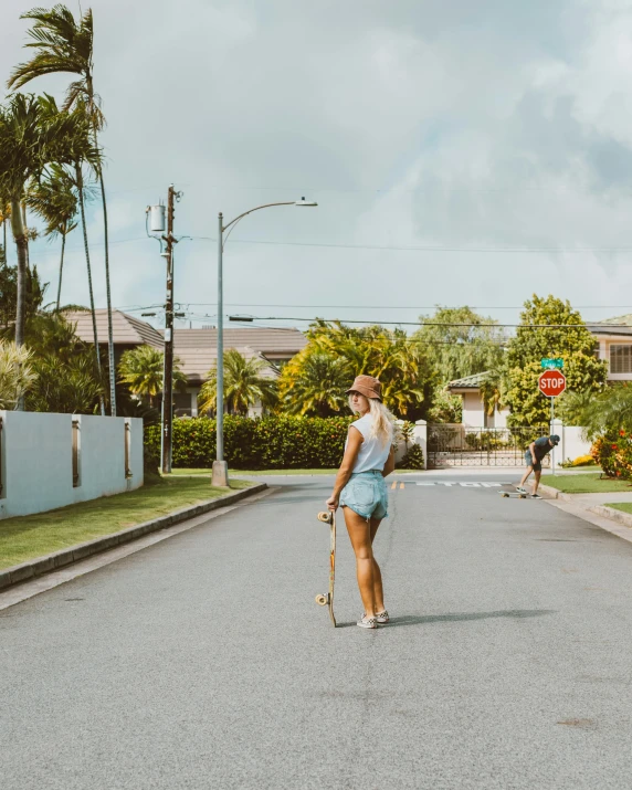 woman walking down the street while holding a skateboard