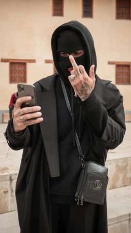 a man wearing a black jacket and a hood using a cell phone