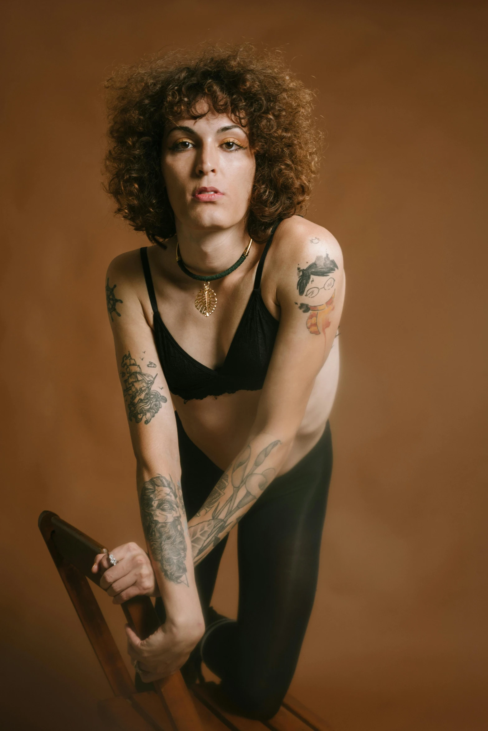 an woman posing in front of a brown backdrop with tattoos on her arms and legs